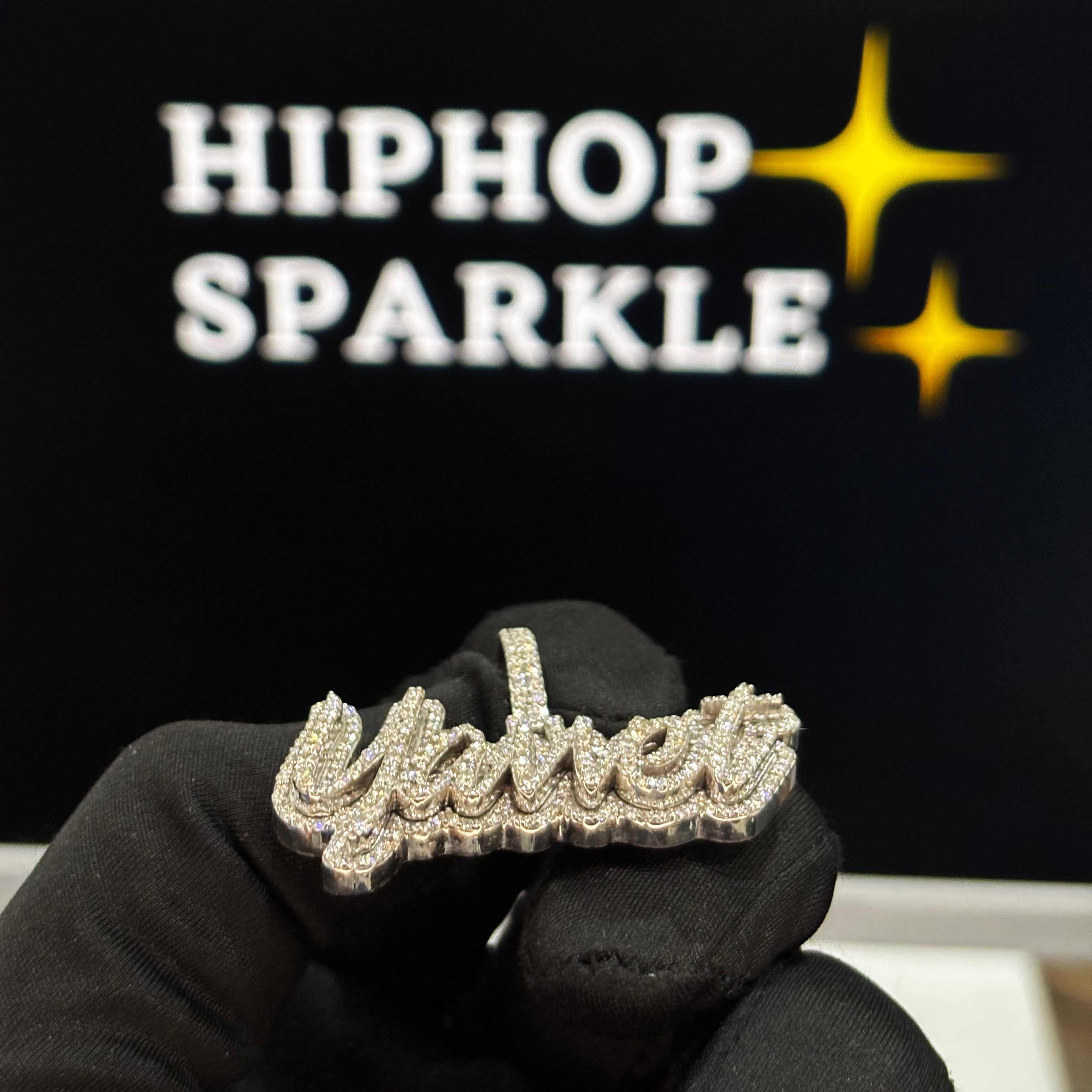 Diamond-encrusted ring held by a gloved hand with 'Hiphop Sparkle' branding in the background.