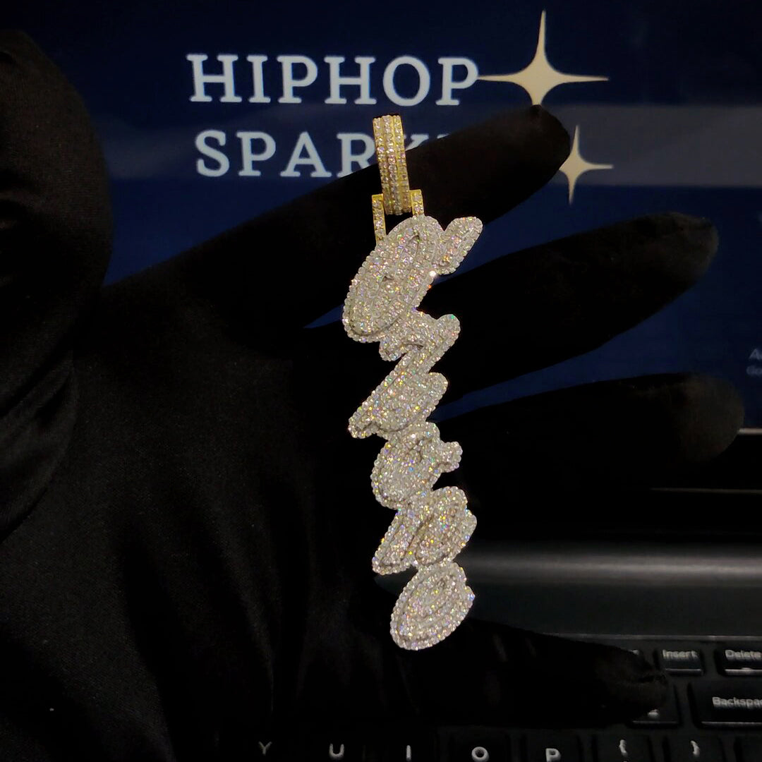Custom iced-out script name pendant with moissanite stones and two-tone bail, held with black gloves – Hip Hop Sparkle jewelry